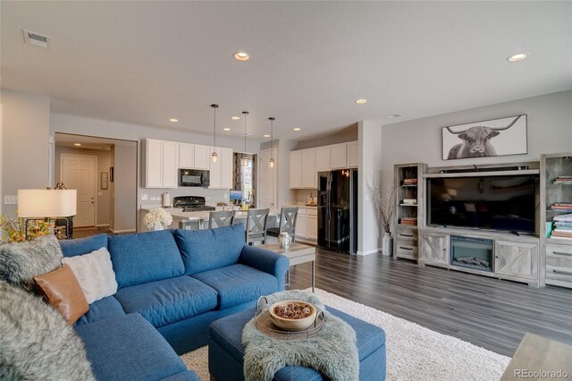 living area with recessed lighting, dark wood-style flooring, and baseboards