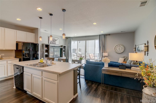 kitchen with black fridge with ice dispenser, dishwasher, open floor plan, a sink, and dark wood-style floors