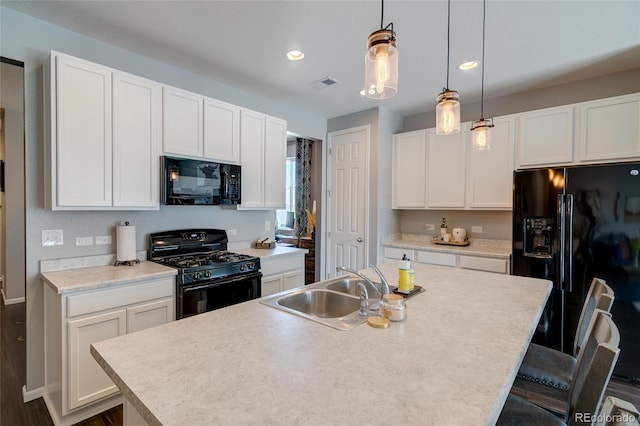 kitchen featuring black appliances, a sink, recessed lighting, white cabinets, and hanging light fixtures