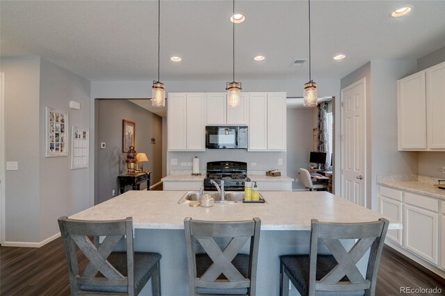 kitchen featuring black appliances, dark wood-style flooring, a kitchen bar, and recessed lighting
