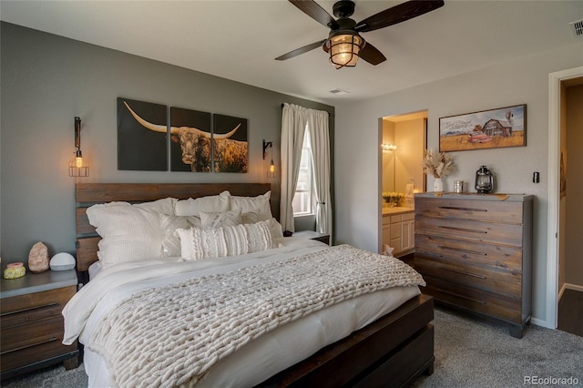 bedroom with dark carpet, ensuite bath, ceiling fan, and baseboards