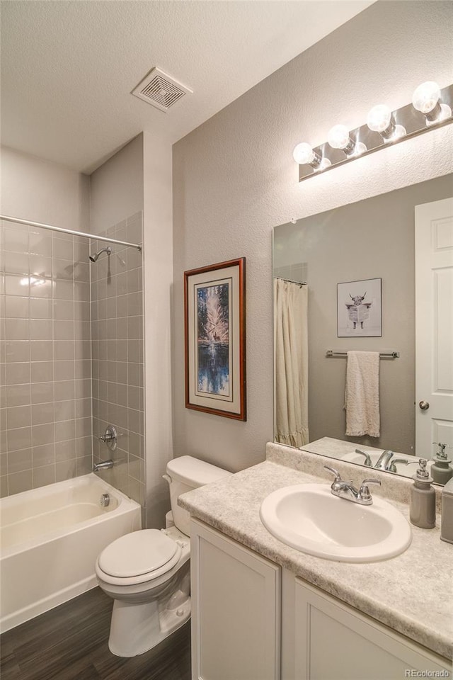 full bath featuring wood finished floors, toilet, vanity, shower / bathtub combination with curtain, and a textured ceiling