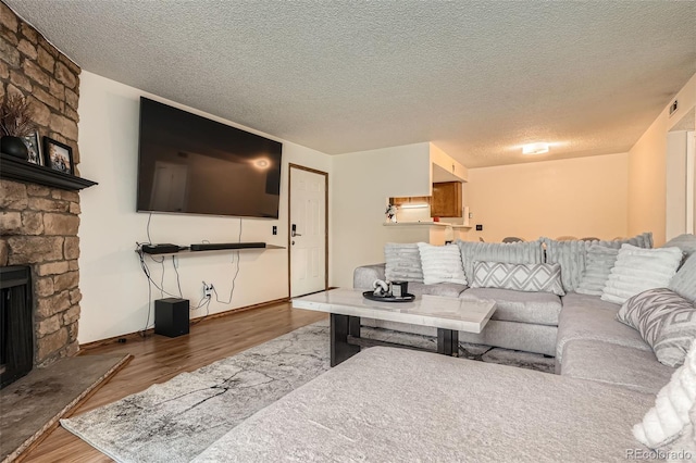 8225 Fairmount Dr Unit 104, Denver, CO 80247 - living room with wood finished floors, a fireplace, a textured ceiling, and baseboards