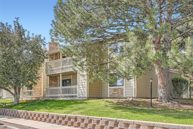 8225 Fairmount Dr Unit 104, Denver, CO 80247 - obstructed view of property featuring a balcony, a front lawn, a chimney, and stone siding