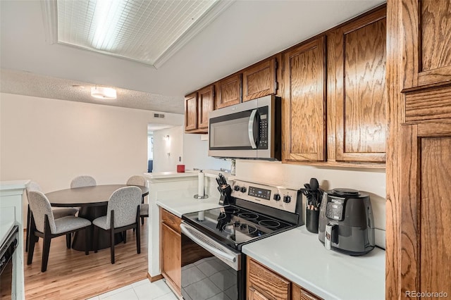 8225 Fairmount Dr Unit 104, Denver, CO 80247 - kitchen featuring appliances with stainless steel finishes, brown cabinetry, light countertops, and light tile patterned floors