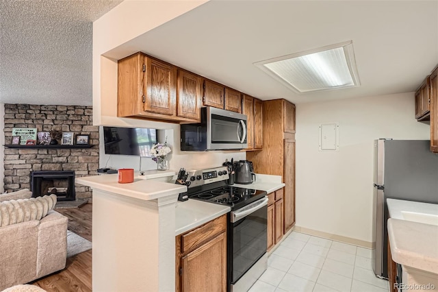 8225 Fairmount Dr Unit 104, Denver, CO 80247 - kitchen with stainless steel appliances, open floor plan, brown cabinetry, light countertops, and a fireplace