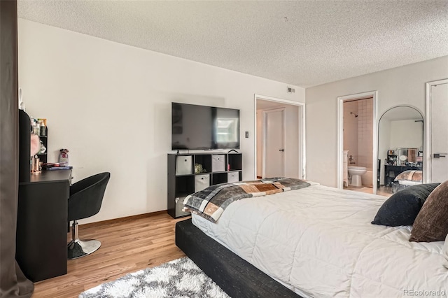 8225 Fairmount Dr Unit 104, Denver, CO 80247 - bedroom featuring light wood-style floors, a textured ceiling, and ensuite bath