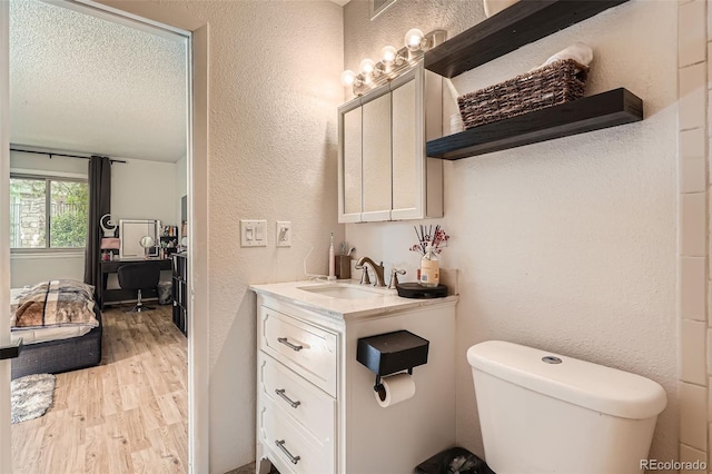 8225 Fairmount Dr Unit 104, Denver, CO 80247 - bathroom featuring wood finished floors, vanity, a textured wall, toilet, and a textured ceiling