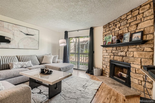 8225 Fairmount Dr Unit 104, Denver, CO 80247 - living area featuring wood finished floors, a stone fireplace, and a textured ceiling