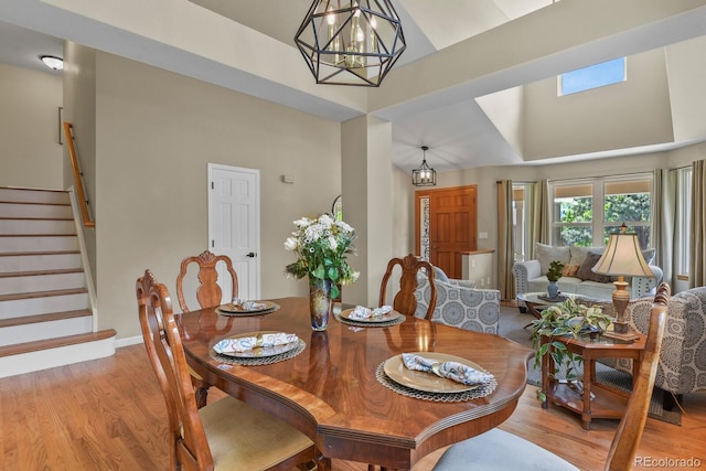 2146 S Ellis Ct, Lakewood, CO 80228 - dining area featuring high vaulted ceiling, light wood finished floors, stairs, and a chandelier
