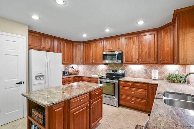 2146 S Ellis Ct, Lakewood, CO 80228 - kitchen with stainless steel appliances, a sink, light tile patterned floors, brown cabinetry, and light stone counters