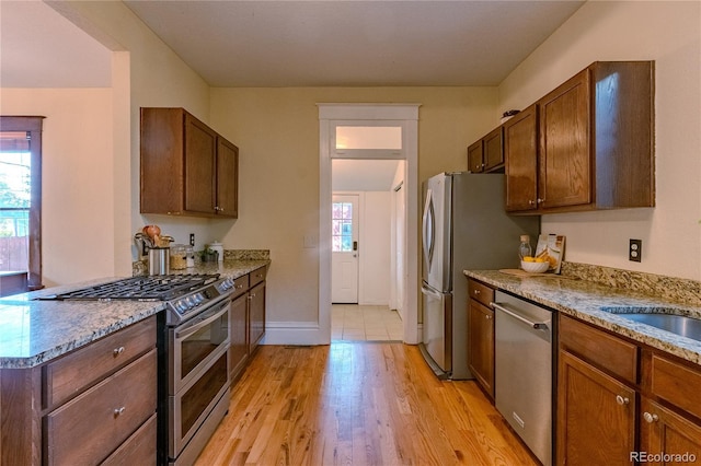 131 Fox St, Denver, CO 80223 - kitchen with stainless steel appliances, healthy amount of natural light, light wood-style flooring, and light stone countertops