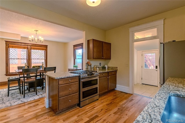 131 Fox St, Denver, CO 80223 - kitchen with stainless steel appliances, a chandelier, light wood-style flooring, and plenty of natural light