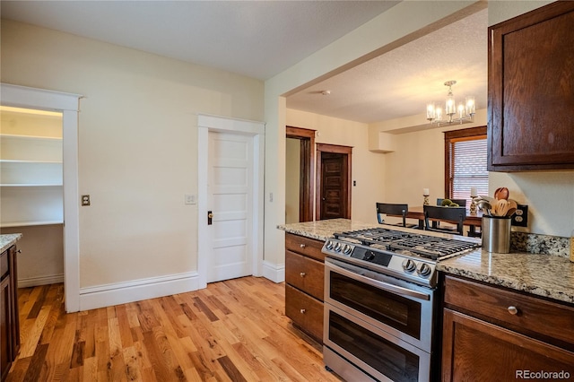 131 Fox St, Denver, CO 80223 - kitchen with double oven range, light wood finished floors, a chandelier, and light stone counters