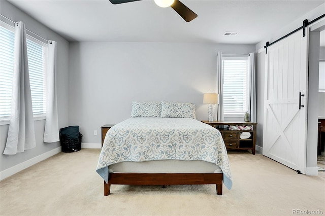 bedroom featuring light colored carpet, a barn door, and ceiling fan