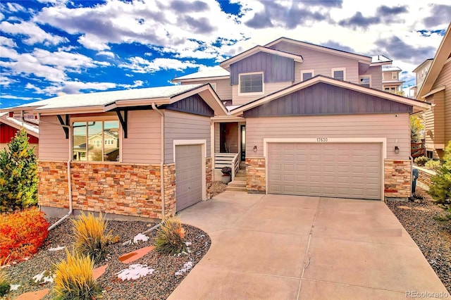 craftsman inspired home with an attached garage, stone siding, driveway, and board and batten siding