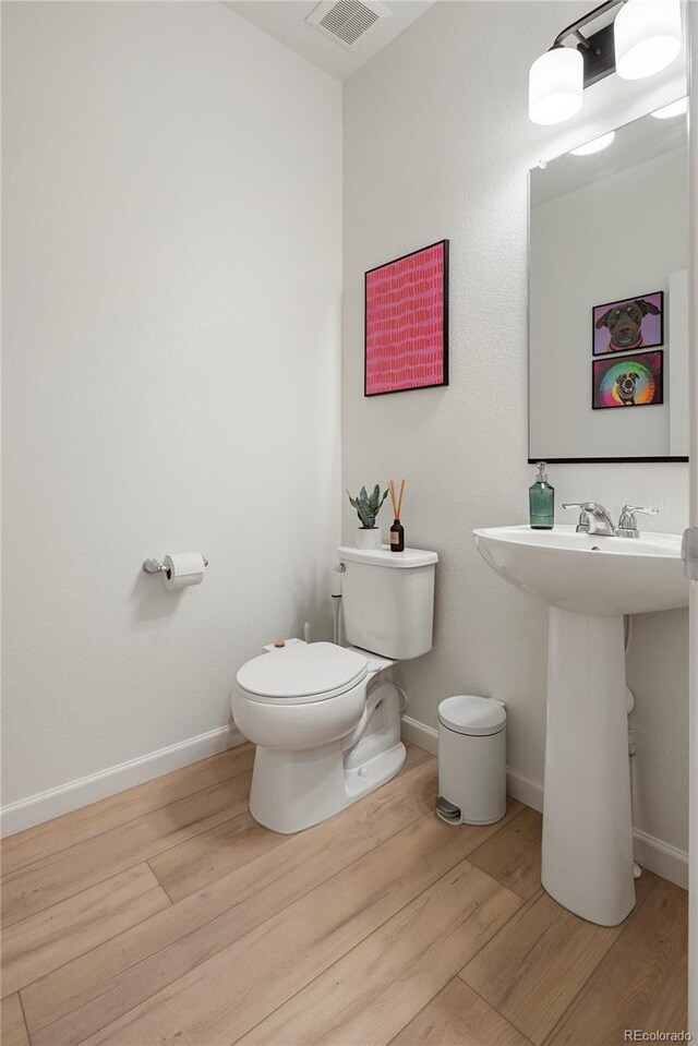 6099 N Netherland Ct, Aurora, CO 80019 - bathroom featuring wood finished floors, toilet, baseboards, and a sink