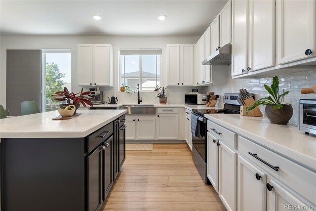 6099 N Netherland Ct, Aurora, CO 80019 - kitchen with electric stove, white cabinets, under cabinet range hood, light countertops, and recessed lighting