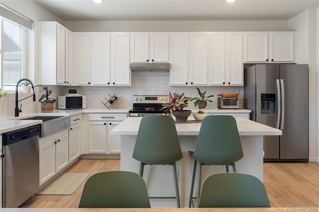 6099 N Netherland Ct, Aurora, CO 80019 - kitchen featuring stainless steel appliances, a sink, white cabinetry, light wood-style flooring, and recessed lighting