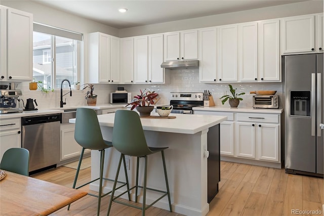 6099 N Netherland Ct, Aurora, CO 80019 - kitchen featuring appliances with stainless steel finishes, under cabinet range hood, a sink, a breakfast bar, and a center island