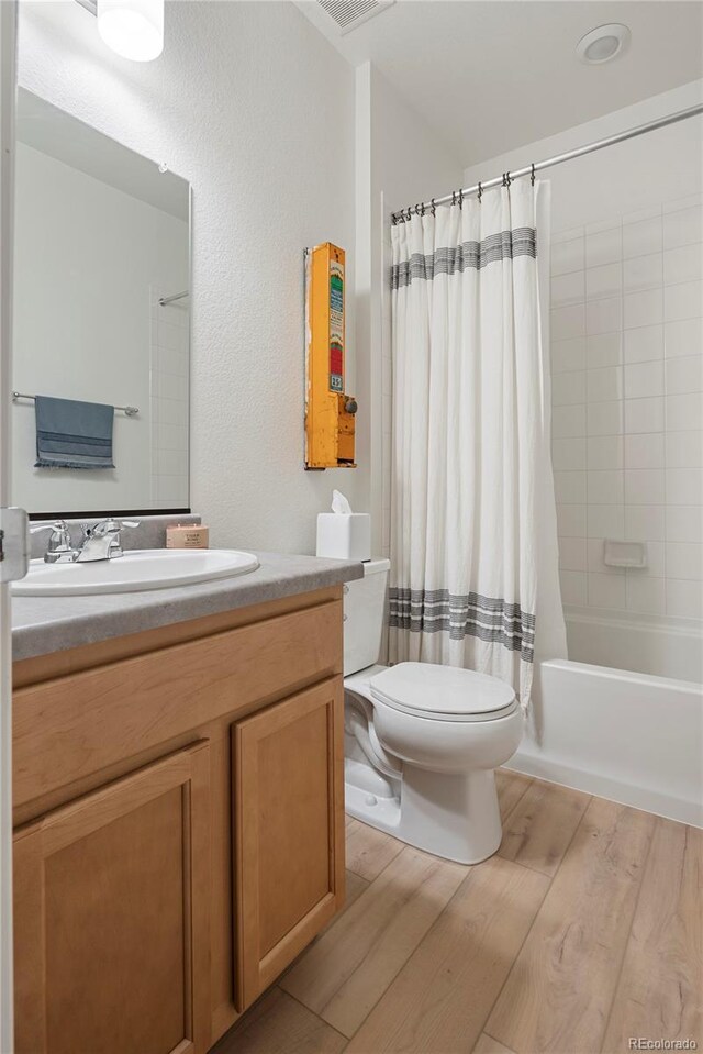 6099 N Netherland Ct, Aurora, CO 80019 - bathroom featuring toilet, vanity, wood finished floors, and shower / tub combo