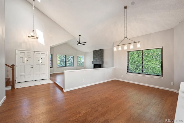 18 Brixham Ct, Castle Pines, CO 80108 - unfurnished living room with wood finished floors, a ceiling fan, a fireplace, baseboards, and a chandelier
