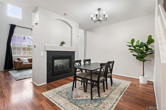 dining space with a multi sided fireplace, plenty of natural light, and dark hardwood / wood-style flooring