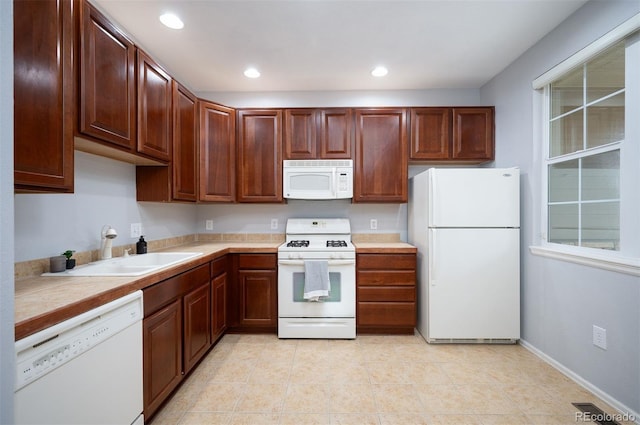 kitchen featuring white appliances, sink, and light tile patterned floors