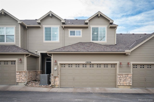 view of front of home with a garage and central air condition unit