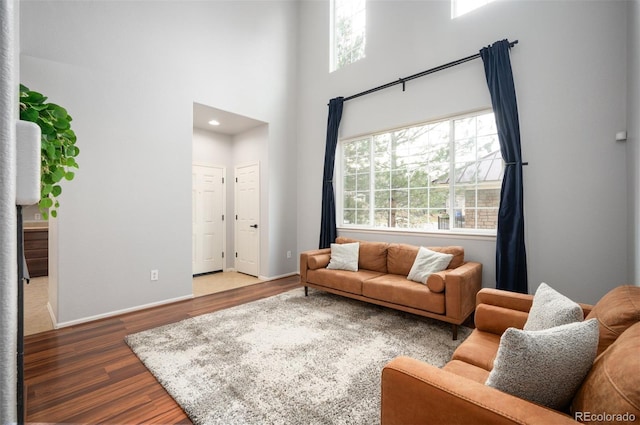 12826 W Brittany Dr, Littleton, CO 80127 - living area featuring wood finished floors, a high ceiling, healthy amount of natural light, and baseboards