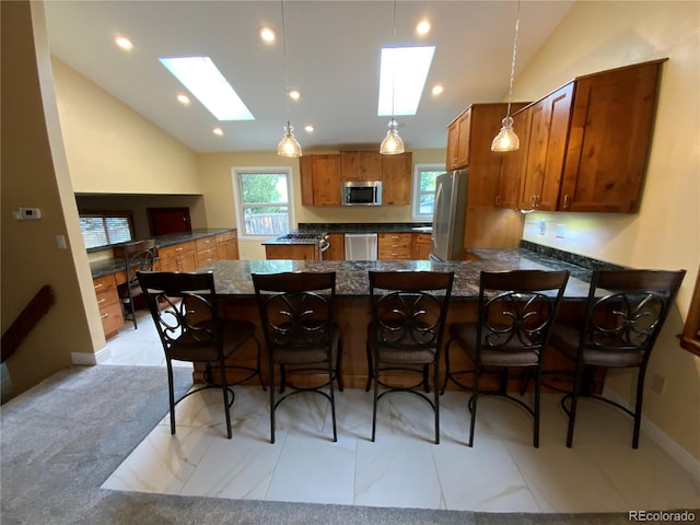 kitchen with hanging light fixtures, kitchen peninsula, stainless steel appliances, lofted ceiling with skylight, and a breakfast bar area