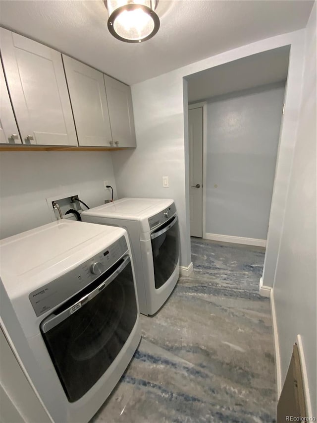 washroom with washer and dryer and cabinets