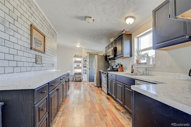 5525 S Johnson Rd, Rush, CO 80833 - kitchen featuring appliances with stainless steel finishes, a sink, light countertops, light wood-style floors, and a textured ceiling