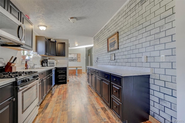 5525 S Johnson Rd, Rush, CO 80833 - kitchen with appliances with stainless steel finishes, brick wall, light wood-style floors, light countertops, and a textured ceiling