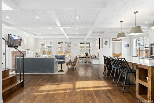 living room with dark hardwood / wood-style flooring, sink, beam ceiling, and plenty of natural light