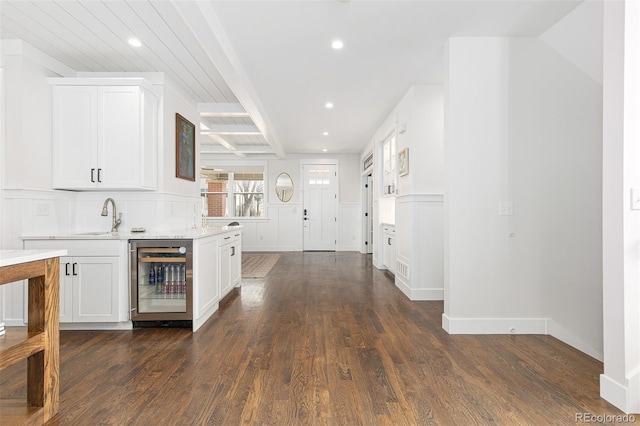 bar with wine cooler, sink, white cabinetry, dark hardwood / wood-style floors, and beam ceiling