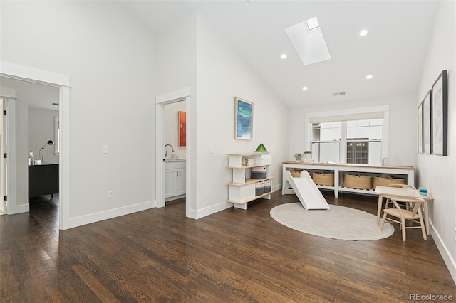 interior space with dark wood-type flooring, sink, a skylight, and high vaulted ceiling