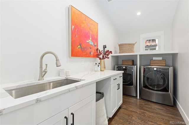 clothes washing area with washer and dryer, sink, dark wood-type flooring, and cabinets