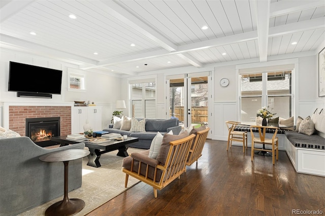 living room featuring dark hardwood / wood-style flooring, a brick fireplace, beam ceiling, and wooden ceiling