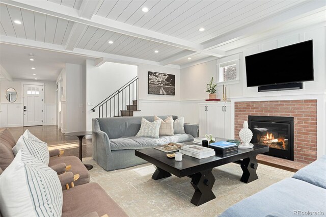 living room with a fireplace, beam ceiling, and wood ceiling