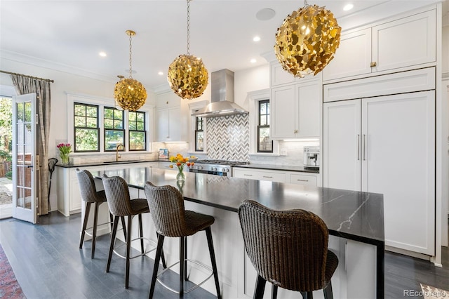 kitchen featuring wall chimney exhaust hood, a kitchen island, and white cabinets