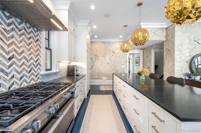 kitchen featuring wall chimney exhaust hood, plenty of natural light, stainless steel stove, and white cabinetry