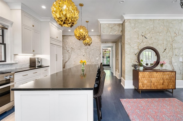 kitchen with white cabinets, hanging light fixtures, dark wood-type flooring, and crown molding