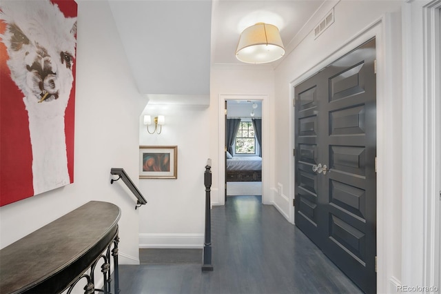 foyer entrance with crown molding and dark wood-type flooring