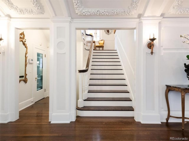 staircase with hardwood / wood-style floors, ornamental molding, and decorative columns