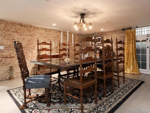 dining space featuring an inviting chandelier and brick wall