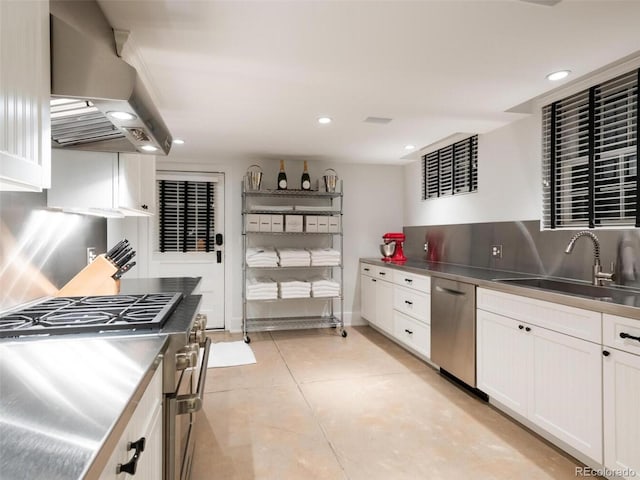 kitchen featuring sink, stainless steel counters, appliances with stainless steel finishes, white cabinetry, and exhaust hood