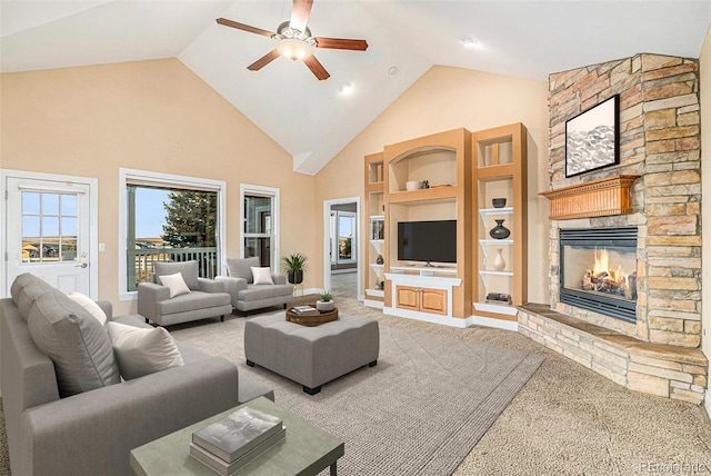 carpeted living room with a fireplace, built in shelves, high vaulted ceiling, and ceiling fan