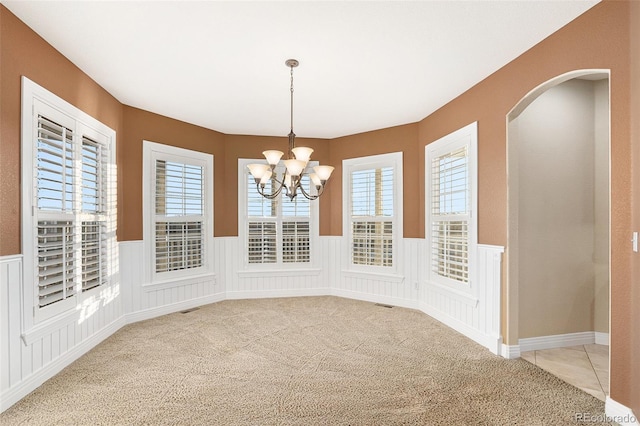 unfurnished dining area with light carpet and a chandelier