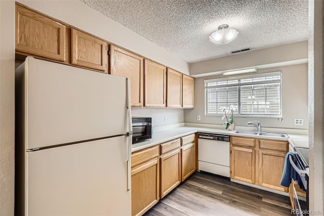 kitchen featuring a sink, a textured ceiling, visible vents, white appliances, and light countertops